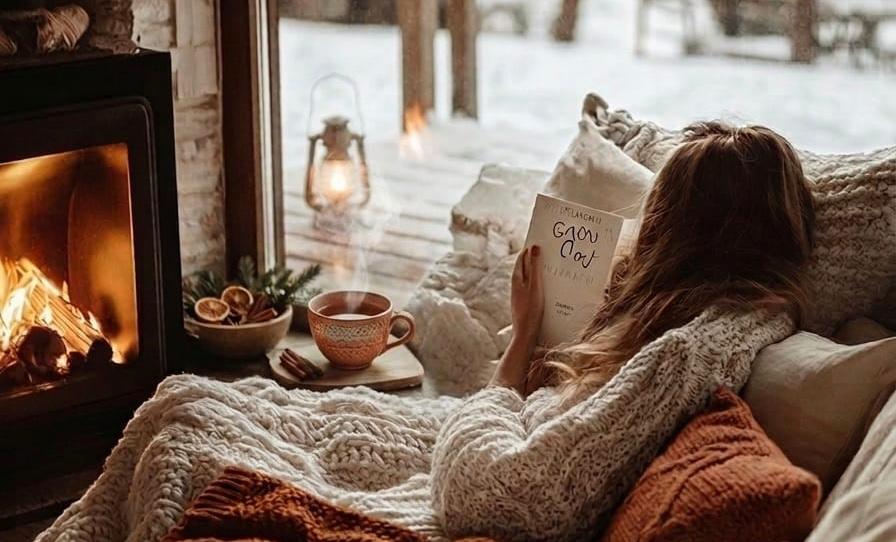 Atmosfera Hygge in una casa del Nord Europa con camino acceso, coperta e tazza calda per il benessere del sistema nervoso