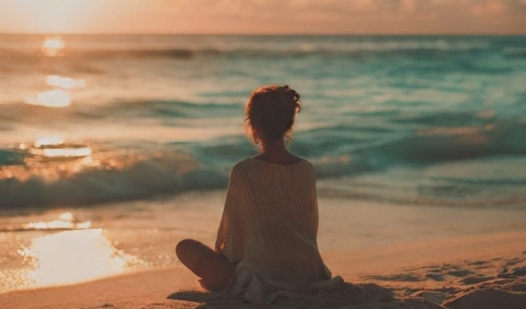 Persona in meditazione al tramonto sul mare che sperimenta la leggerezza interiore
