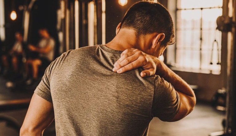 Ragazzo sportivo che sente dolore muscolare in palestra