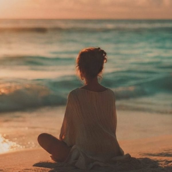Persona in meditazione al tramonto sul mare che sperimenta la leggerezza interiore