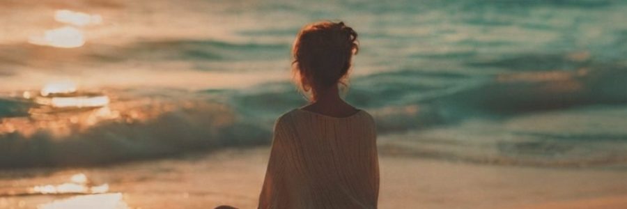 Persona in meditazione al tramonto sul mare che sperimenta la leggerezza interiore