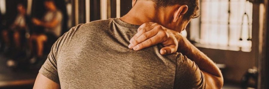 Ragazzo sportivo che sente dolore muscolare in palestra